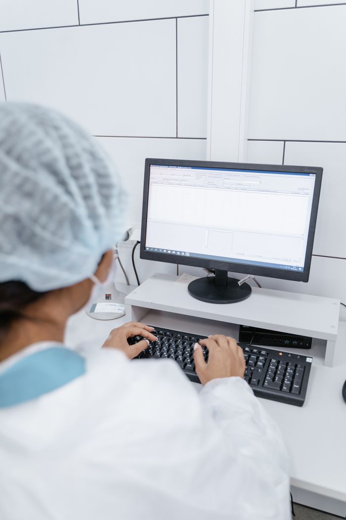 Home A medical professional working on a computer in a laboratory setting, focusing on data analysis.