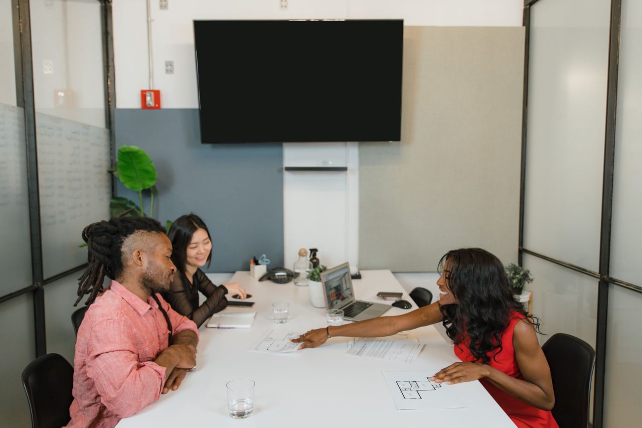 Mastering the First Impression: Your intriguing post title goes here Three professionals engaged in a collaborative meeting in a modern office setting.