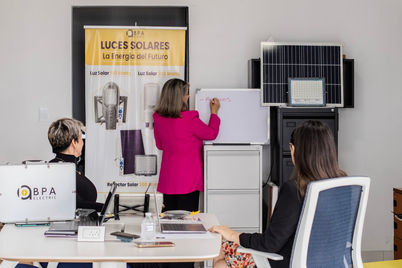 about-us-01 A team engaged in brainstorming solar energy solutions with panels and a whiteboard in an office.