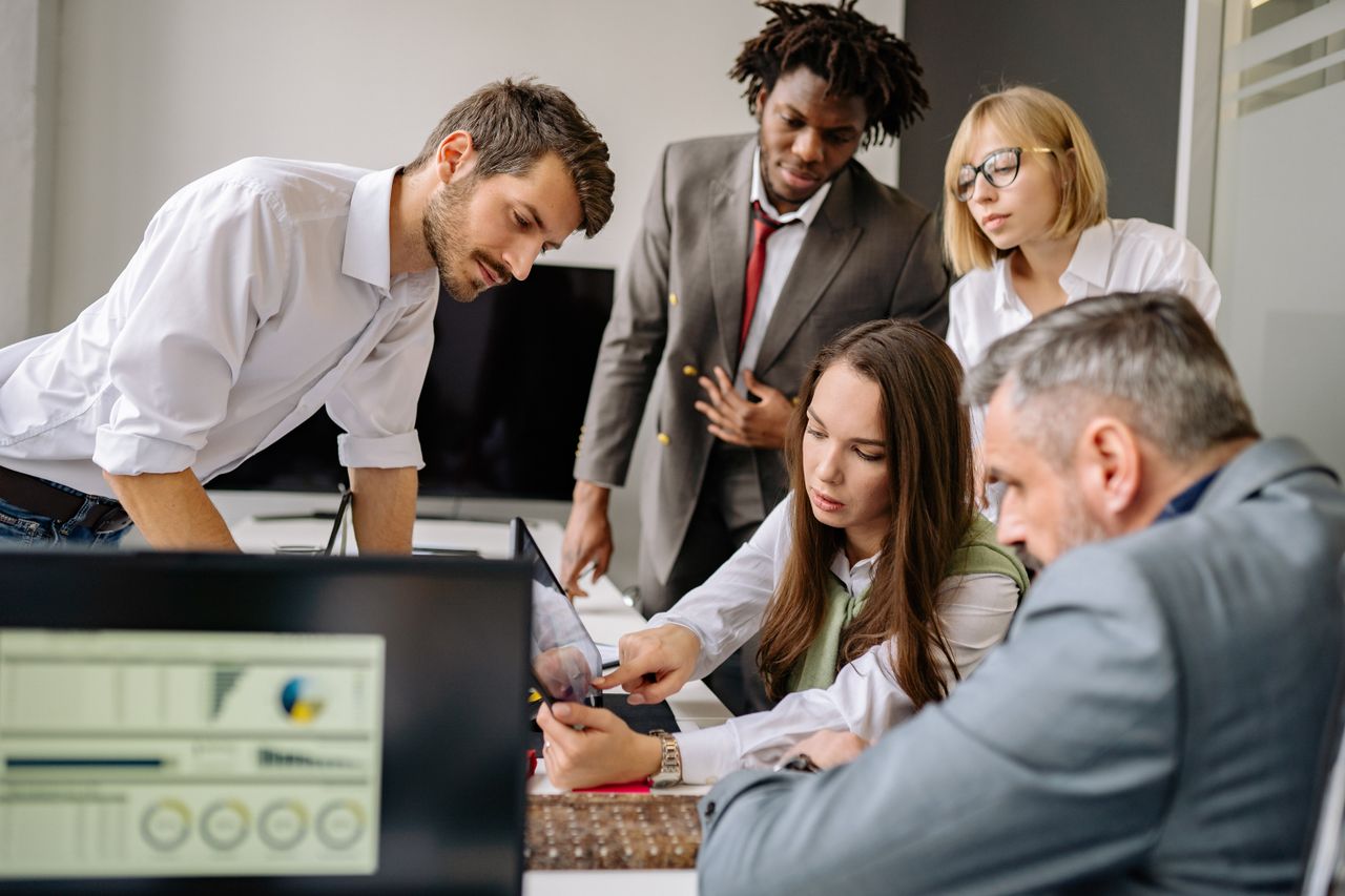 services-02 A diverse team engages in a collaborative meeting in a modern office setting, focused on digital analysis.