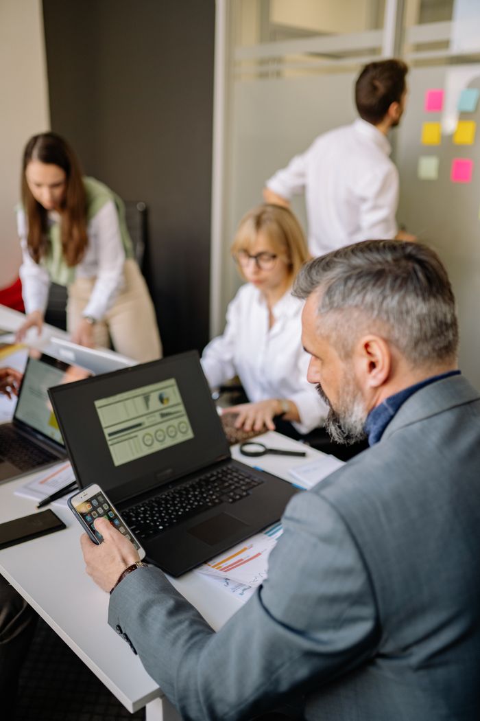 about-us-02 Corporate team working together with technology in a modern office setting, promoting collaboration and productivity.
